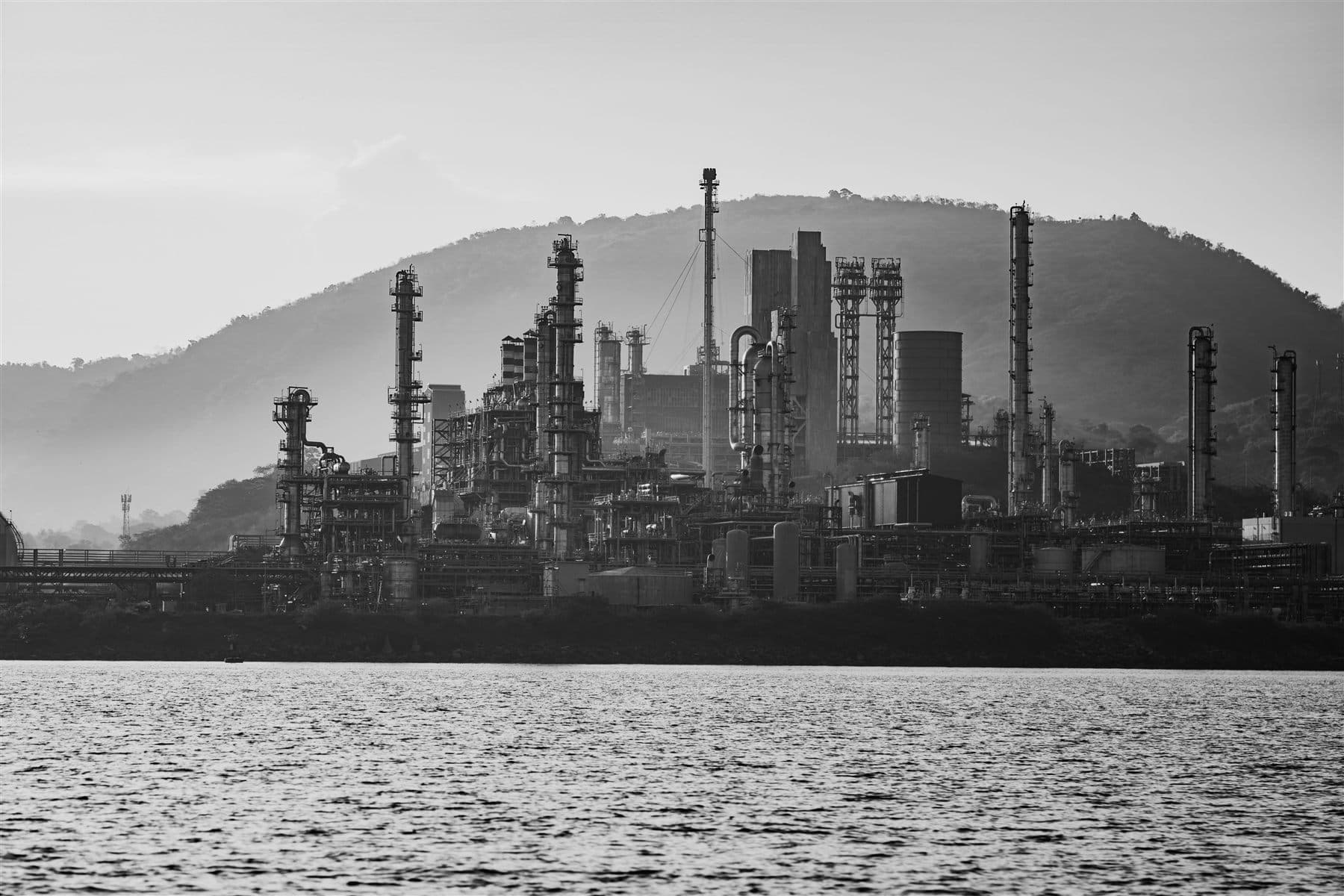 Industrial refinery silhouetted at dusk across the water