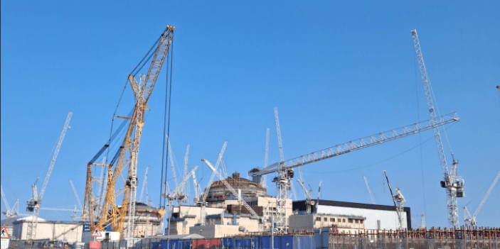 Nuclear power plant under construction, cranes against a clear sky